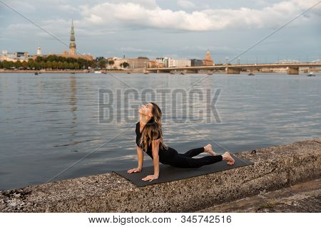 Yoga Meditation And Wellness Lifestyle Concept. Fit Slim Woman Practicing Yoga Exercises Near River 