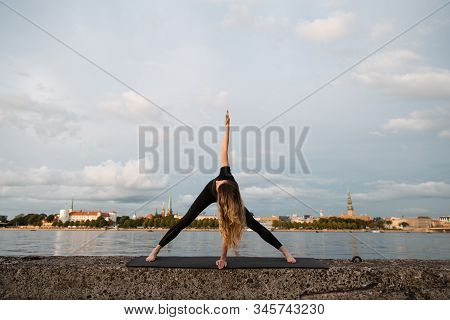Yoga Meditation And Wellness Lifestyle Concept. Fit Slim Woman Practicing Yoga Exercises Near River 