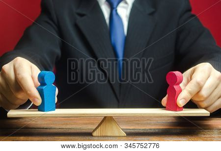 The Figure Of A Man And A Woman On Scales. Gender Pay Gap. Equality, Inequality. The Concept Of Divo