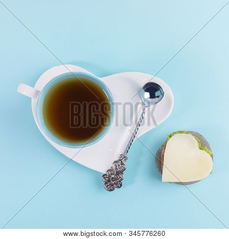Cup Of Tea And Silver Spoon On Saucer In Heart Shape And Sandwich With Cheese And Herbs In Heart Sha