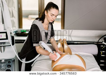 Cropped Close Up Of Professional Female Cosmetologist Using Ultrasound Cavitation Or Roller Machine 