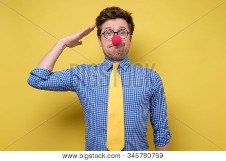 Young Patriotic Man Dressed As Clown Making Salute Gesture And Ready To Do Order With Funny Face.