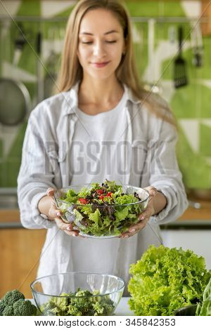 Cheerful Slim Girl Enjoying Vegetable Salad In Glass Bowl Over Kitchen Background, Vertical Panorama