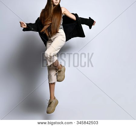 Brunette Adolescent With Long Hair, In Striped T-shirt, Black Denim Jacket, Beige Pants And Sneakers
