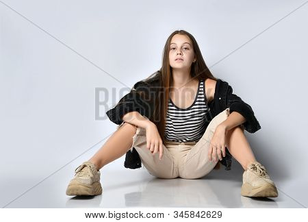 Teenage Female With Long Hair, In Striped T-shirt, Black Denim Jacket, Beige Pants And Sneakers. She