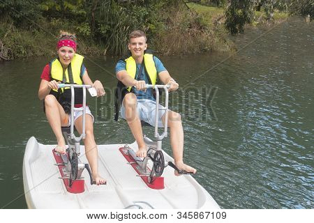 Happy Couple Riding A Catamaran, Smiling. Water Transport, Carriage. Water Bicycle. Boy And Girl In 