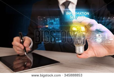 Businessman holding lightbulb with INFORMATION SECURITY inscription, online security idea concept