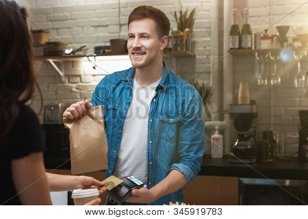 Hospitable Barista Man Standing Behind Bar Sells Hot Coffee Drink And Lunch In Paper Bag To Woman Cl