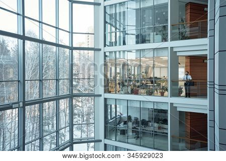 Interior of contemporary multi-floor business center with large windows and many offices in front of them