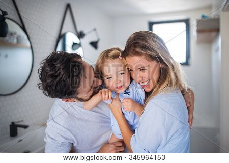 Young Family With Small Daughter Indoors In Bathroom, Hugging.