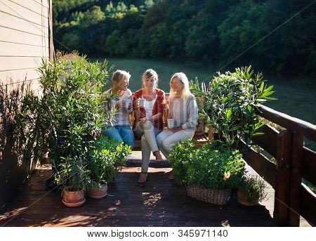 Senior Women Friends Sitting Outdoors On Terrace, Resting.