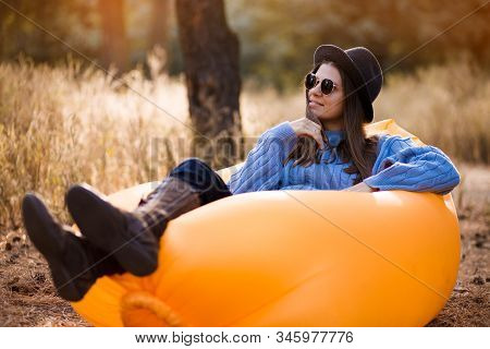 Autumn Lifestyle Portrait Of Pretty Girl In Stylish Sunglasses And Black Hat Sitting On Orange Infla