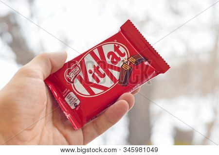 Kit Kat Chocolate Bar In Male Hand On Snowy Background. Kit Kat Created By Rowntrees Of York In Unit