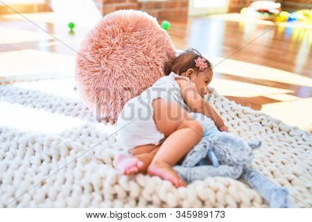 Beautiful infant happy at kindergarten around colorful toys lying on blacket