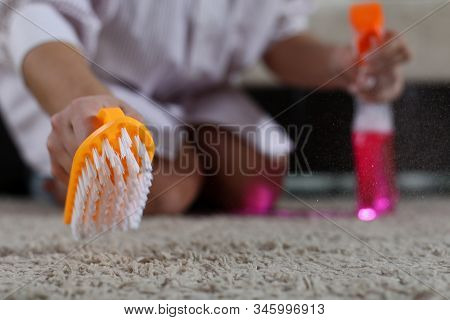Close-up Of Female Hand Holding Detergent Pink Spray And Brush Cleaning Carpet At Home. Woman Janito