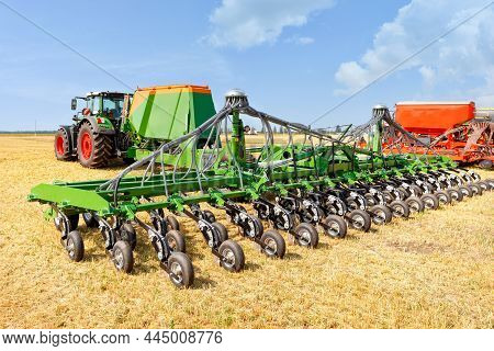 Modern Agricultural Seeders With Pneumatic Distribution Mechanism Against A Blue Cloudy Sky On A Sum