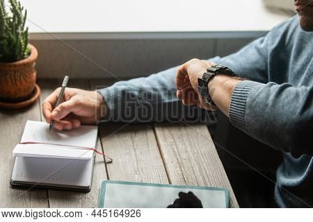 A Man-businessman Makes Notes In A Weekly, In A Notebook, He Has A Black Watch On His Hand, And He C