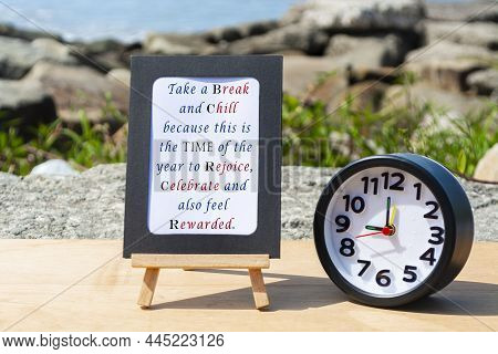 Motivational And Inspirational Quote On Standing Notepad With Black Alarm Clock. Blurred Beach Backg