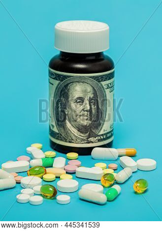Money And Pills Of Different Colors On A Blue Background. The Rise In The Cost Of Medical Care. The 