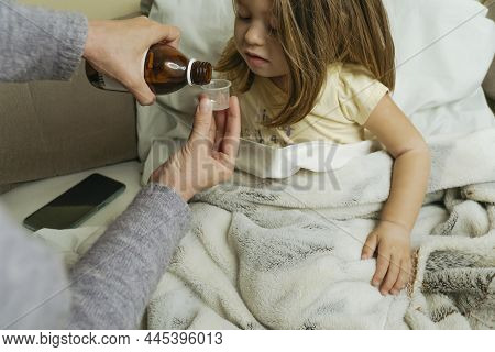 Female Hands Pour Medicine For Sick Little Girl