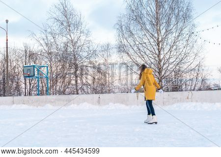 Young Woman In Yellow Jacket Skating At The Rink