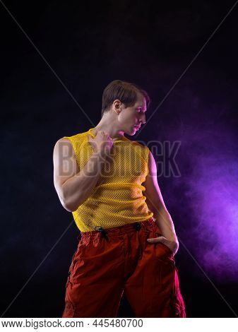 A Young Muscular Man In A Bright Outfit Poses In A Pretentious Pose, Style And Grotesque. Attractive