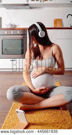 Pregnant Doing Workout On Orange Fitness Mat. Pragnant Yoga At Home In The Kitchen. Pregnant In Whit