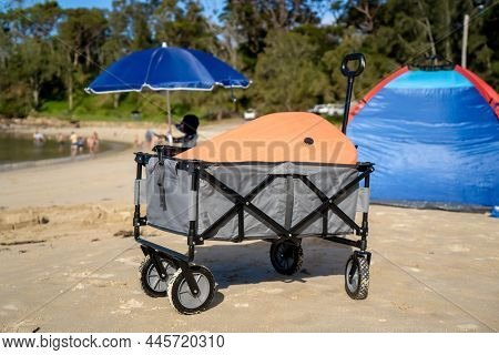 Outdoor Beach Cart Wagon And Beach Tent Sun Shelter On A Sandy Beach Near The Ocean. Family Vacation