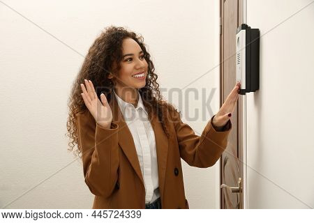 Young African-american Woman Ringing Intercom While Waving To Camera In Entryway