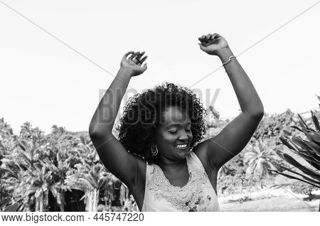 Black Woman In Black And White Portrait Posing For Photo With Trees In Background.