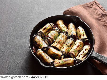 Eggplant (aubergine) Rolls With Cheese And Greens In Frying Pan Over Dark Stone Background.