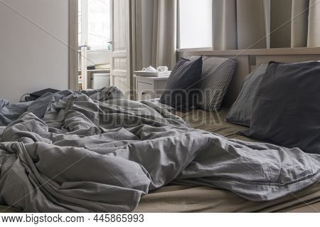 An Unmade Bed With Two Duvets In Gray Duvet Covers. Morning Concept