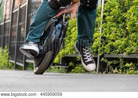 Riding An Electric Unicycle (euc). A Rider In Protective Knee Pads Falls From An E-monowheel.