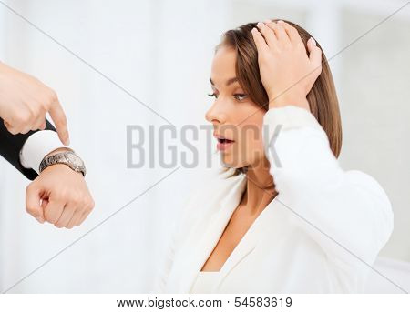 business and time management concept - boss showing watch to stressed businesswoman