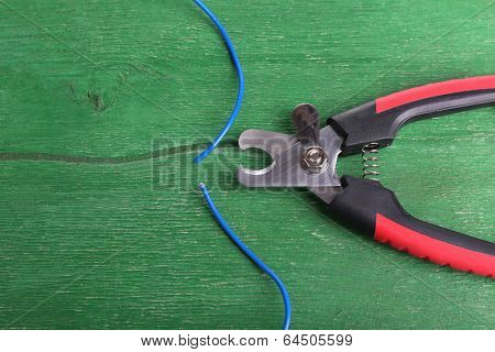 Side cutters cut cable on wooden background