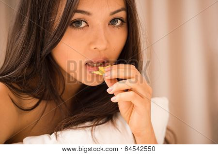 Asian Young Woman Eating Potato On The Bed In The Hotel Room