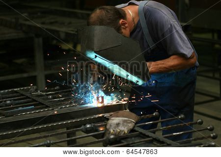 Welder in a workshop making a fence