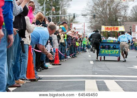 Spectators Cheer Team Pushing Bed Toward Finish Of Fundraiser Race