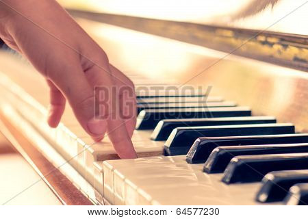 Little Girl Playing On Piano. Warm Color Toned Photo