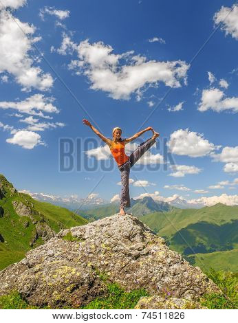 Young woman exercises yoga in the mountains