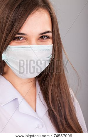 Doctor / Nurse Smiling Behind Surgeon Mask. Closeup Portrait Of Young  Caucasian Woman Model In Whit