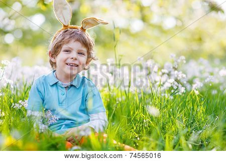 Cute Happy Little Kid Wearing Easter Bunny Ears At Spring Green Grass