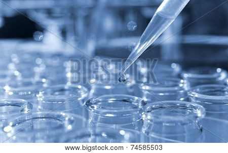 Glass measurer dripping fluid into tubes