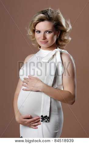 Smiling pregnant girl against beige background.
