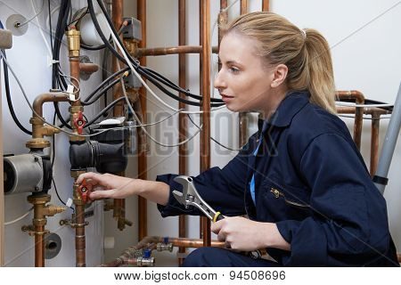 Female Plumber Working On Central Heating Boiler