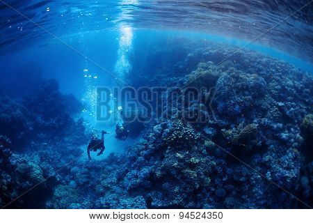 Underwater shot of two divers exploring underwater canyon. Red Sea, Egypt