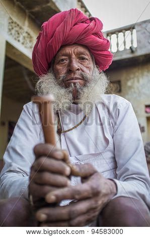 GODWAR REGION, INDIA - 12 FEBRUARY 2015: Elderly Rabari tribesman with traditional turban, clothes and long beard holds chillum. Rabari or Rewari are an Indian community in the state of Gujarat.