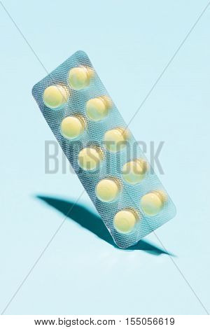 Yellow oral contraceptive pill strips on blue background with shadow.
