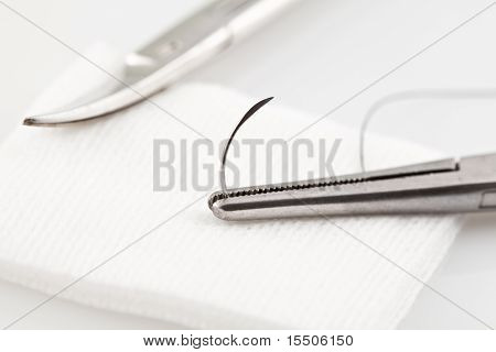 Zavřít obrázek chirurgického šicího materiálu s nůžkami v pozadí