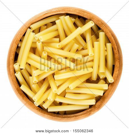 Macaroni pasta in wooden bowl, Italian maccheroni, short-cut noodles in the shape of narrow tubes. Uncooked dried durum wheat semolina pasta. Isolated macro food photo over white background.